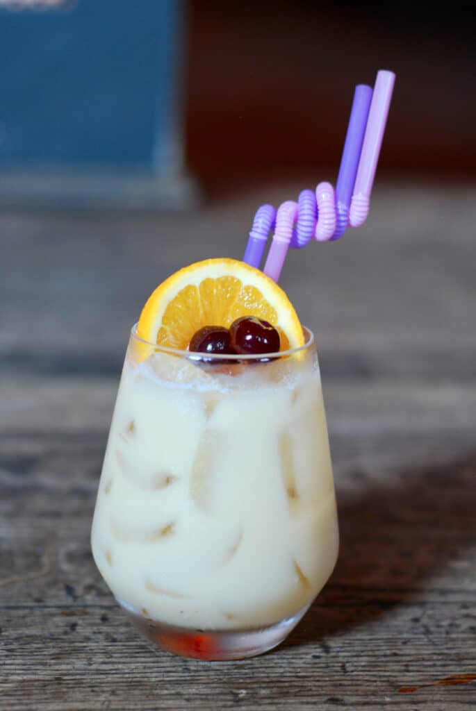 a cocktail with cherries and an orange slice on top